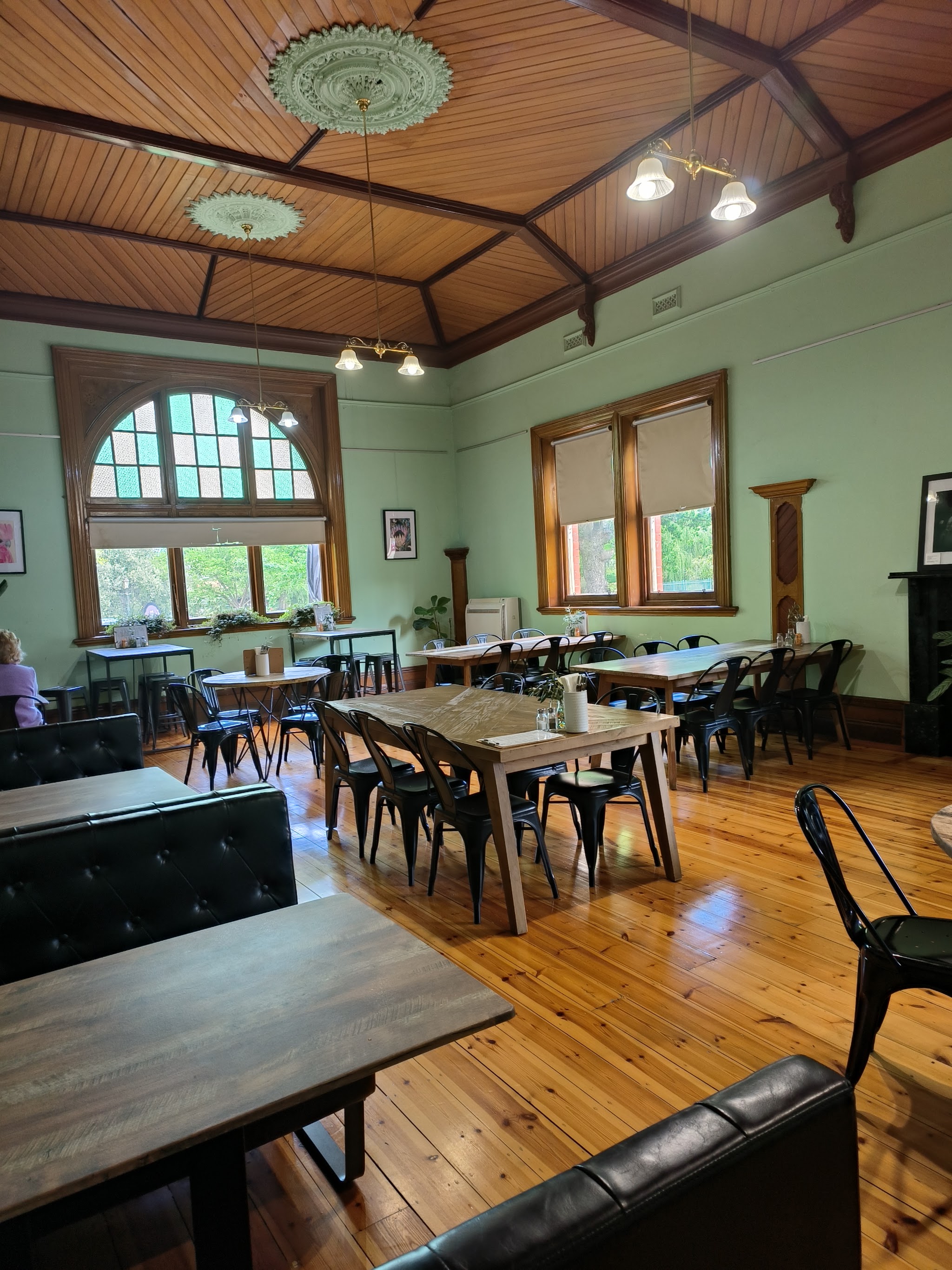 Inside The Shire Cafe: sage green walls, a timber lined ceiling with plaster roses, and an arched leadlight window
