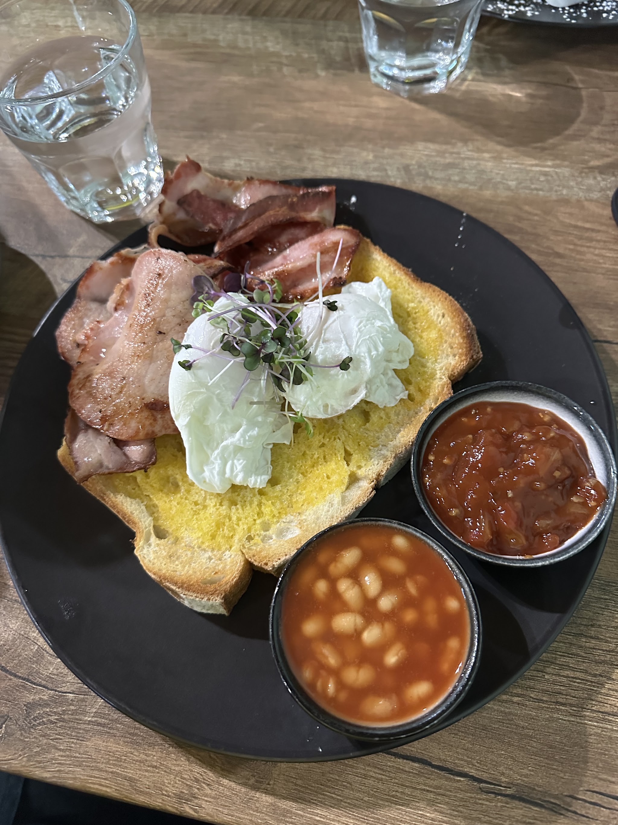 Bacon and poached eggs on thick toast with baked beans and tomato relish