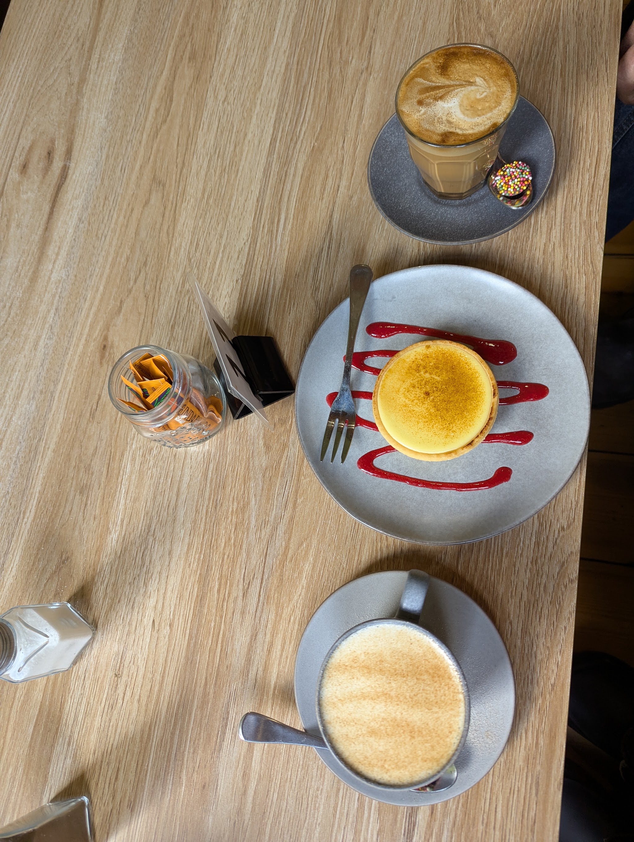 A latte, a cappuccino and a lemon tart with raspberry coulis